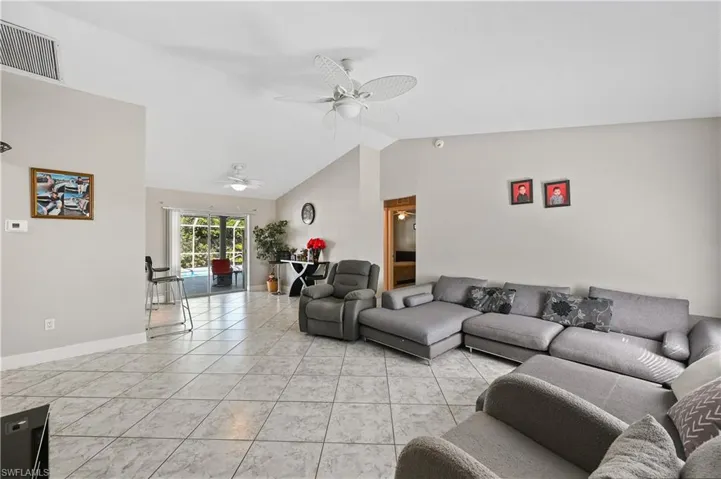 Living area with light tile patterned flooring, lofted ceiling, and a ceiling fan