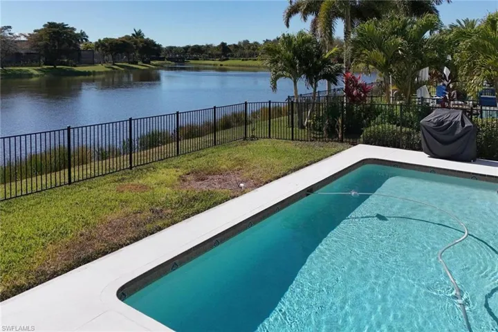 View of pool featuring a fenced backyard, patio surround, a grill, and a water view