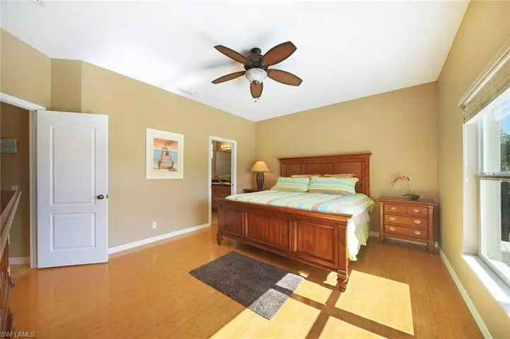 Bedroom with light wood-style flooring, a ceiling fan, and ensuite bath