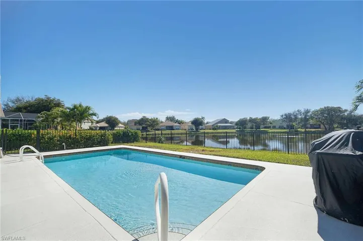 View of pool featuring a fenced backyard, grilling area, a residential view, patio surround, and a water view