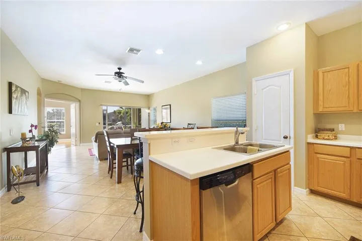 Kitchen featuring stainless steel dishwasher, an island with sink, light countertops, open floor plan, and a breakfast bar area