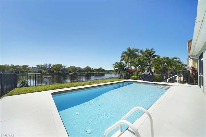 View of pool with patio surround, a fenced backyard, and a water view