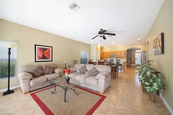 Living room featuring arched walkways, a ceiling fan, light tile patterned flooring, and recessed lighting