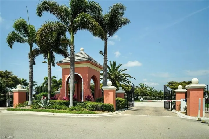 View of asphalt road with a gate, curbs, and a gated entry