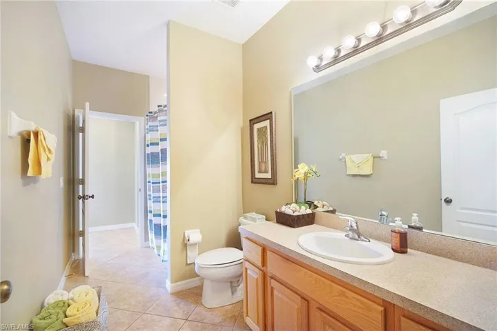 Full bath featuring a shower with shower curtain, vanity, and light tile patterned floors