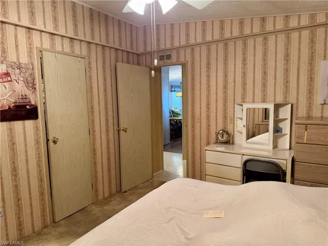 Bedroom with ceiling fan, carpet, and wallpapered walls