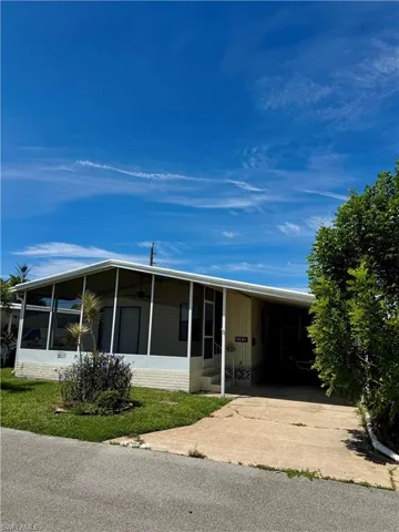 Rear view of property featuring a sunroom, driveway, and a carport