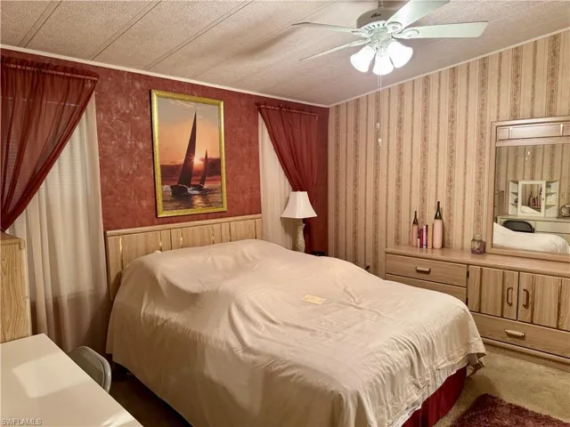 Bedroom featuring ceiling fan, wallpapered walls, and carpet floors