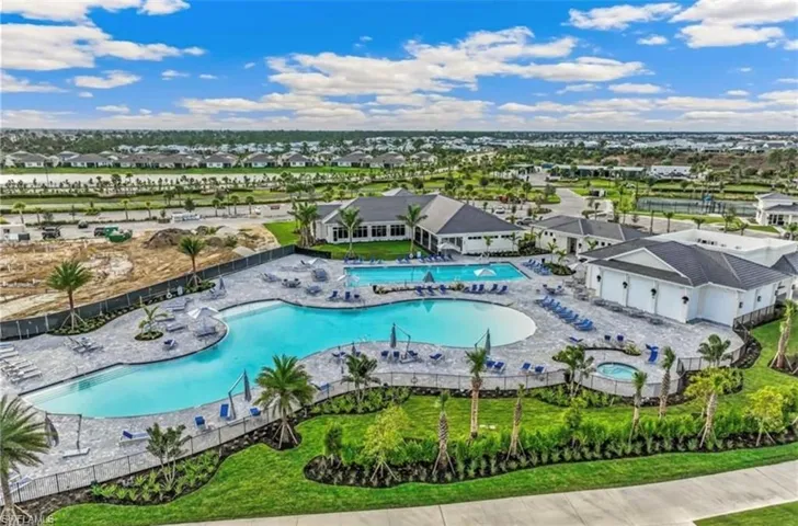 Expansive community pool area featuring a large lagoon-style pool, a rectangular lap pool, and an integrated spa