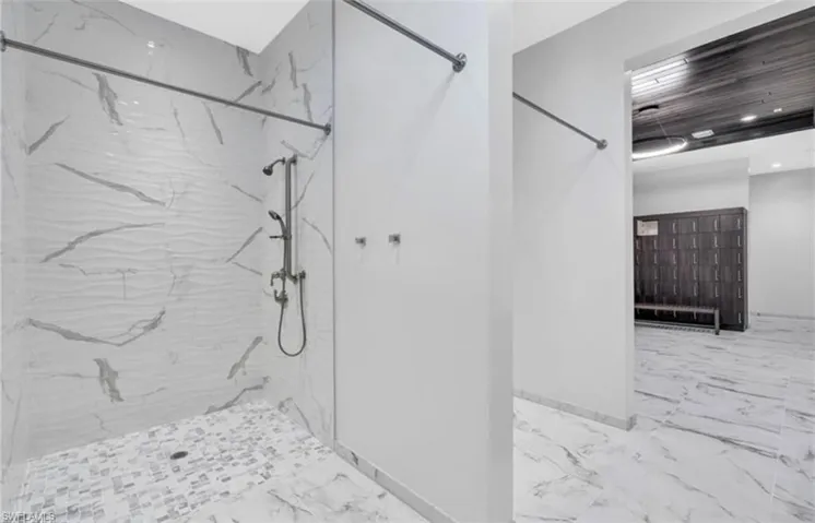 Shower stall featuring textured wave-patterned wall tiles and mosaic floor tiles