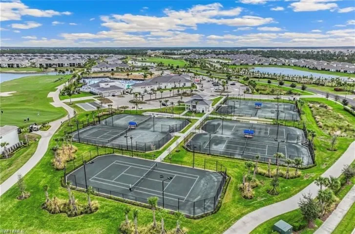 Multiple tennis courts surrounded by manicured landscaping