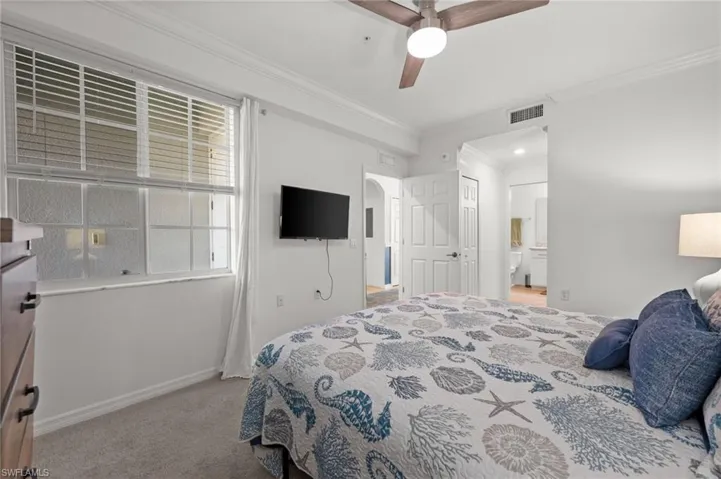 Carpeted bedroom featuring a ceiling fan with light fixture, crown molding, and white window blinds