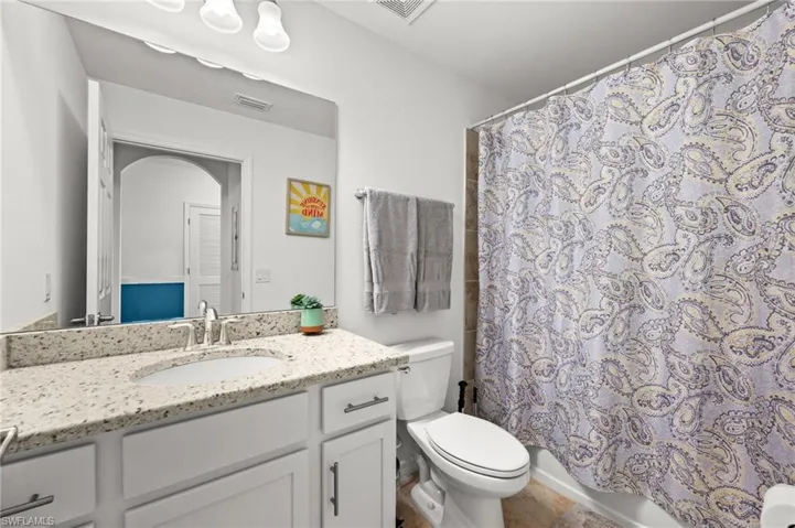Bathroom featuring a single vanity with a light-colored speckled countertop, an undermount sink, and a chrome faucet