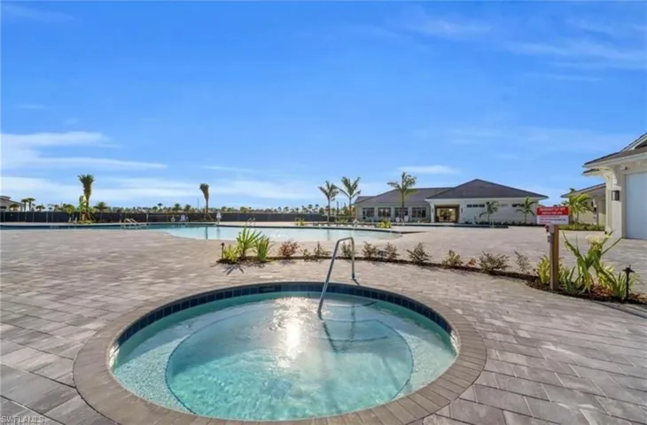 Circular spa with integrated steps and a stainless steel grab rail, set within a paver patio
