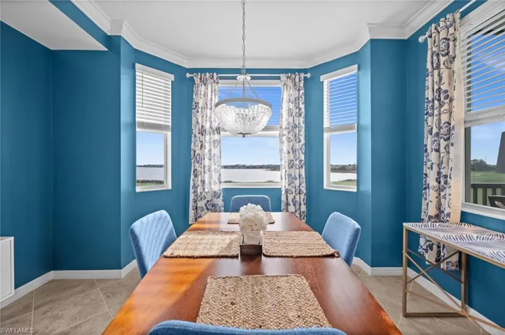Bay window dining area featuring a crystal chandelier, crown molding, and tile flooring