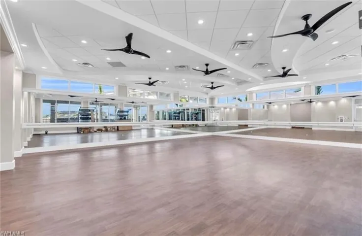 Spacious open room featuring wood-finish flooring, full-height wall mirrors, and integrated ballet barres
