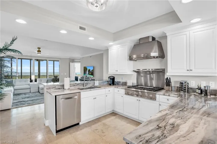 Kitchen with ceiling fan, wall chimney exhaust hood, sink, appliances with stainless steel finishes, and kitchen peninsula