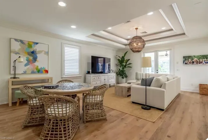 Living room with light wood-style flooring, crown molding, recessed lighting, and a tray ceiling