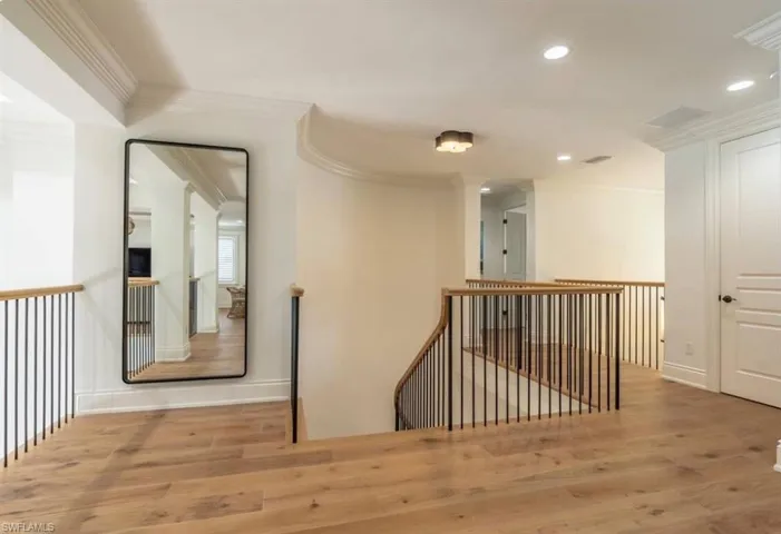 Hallway with an upstairs landing, wood finished floors, ornamental molding, and recessed lighting