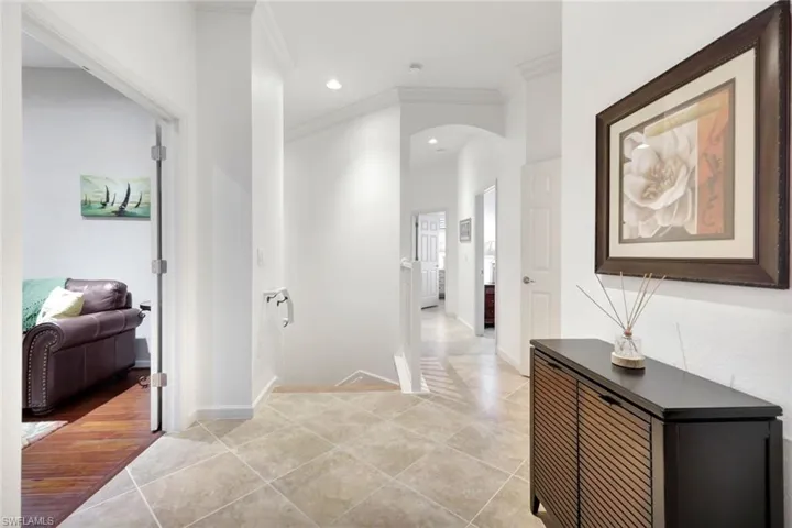 Hall with crown molding, light tile patterned flooring, arched walkways, and recessed lighting