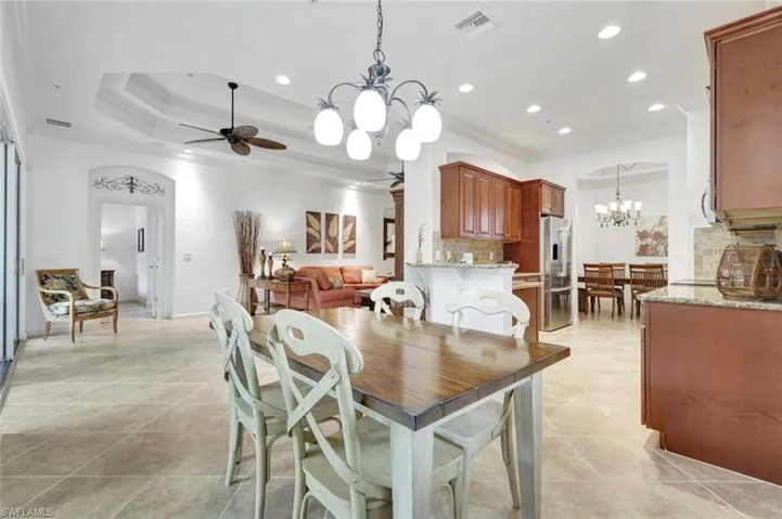 Dining area with a chandelier, recessed lighting, ornamental molding, light tile patterned floors, and a tray ceiling