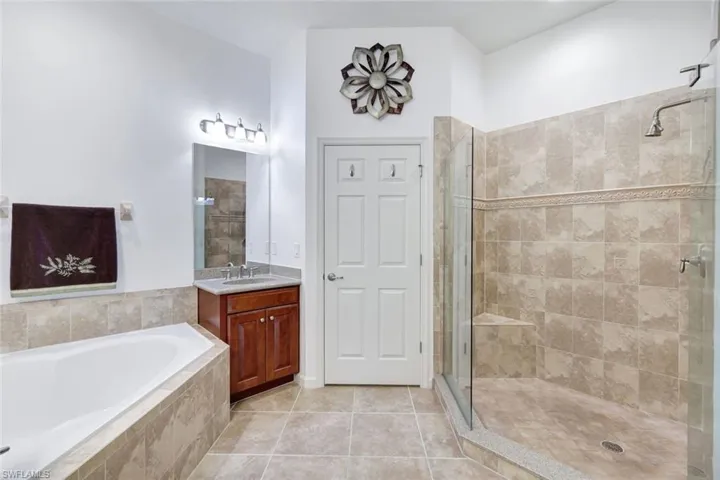 Full bathroom featuring a bath, light tile patterned floors, vanity, and a stall shower