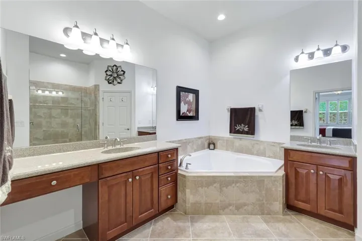Full bath with a shower stall, two vanities, a garden tub, light tile patterned flooring, and recessed lighting