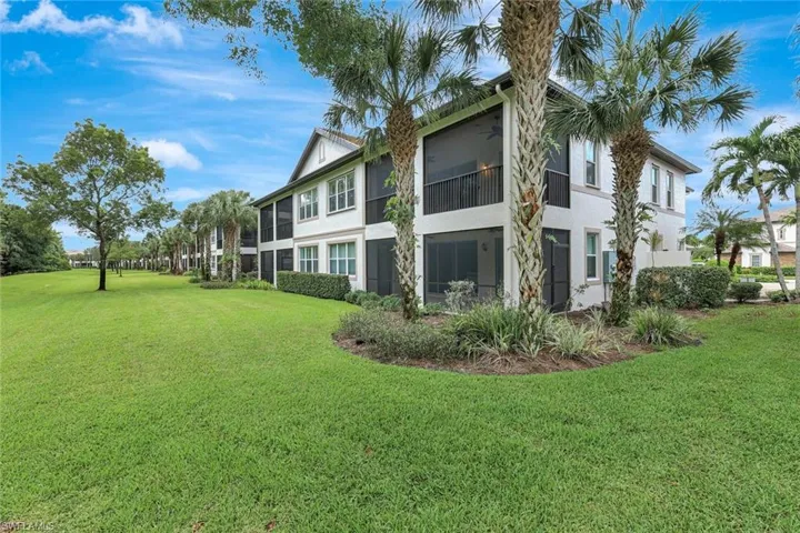 Rear view of property featuring a lawn, stucco siding, a sunroom, and a balcony