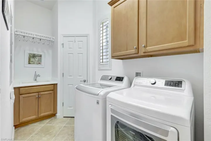 Laundry area featuring cabinet space, light tile patterned flooring, and washer and clothes dryer
