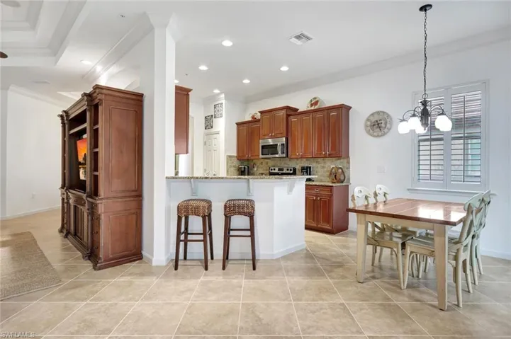Kitchen featuring a kitchen bar, light stone countertops, recessed lighting, decorative backsplash, and a peninsula