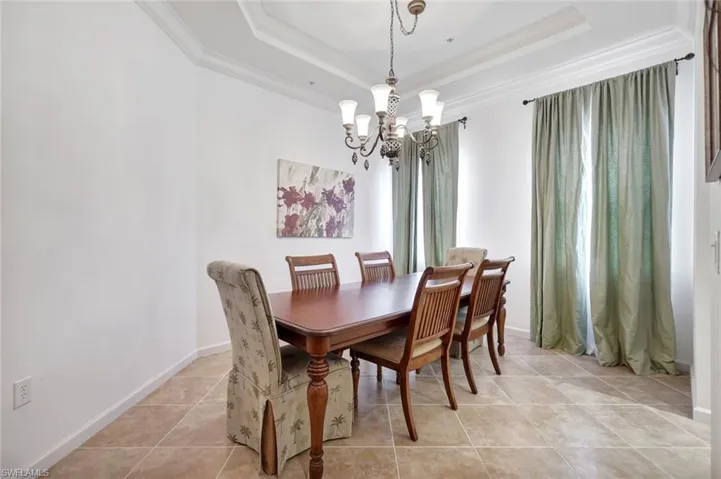 Dining room featuring a chandelier, ornamental molding, a raised ceiling, and light tile patterned floors