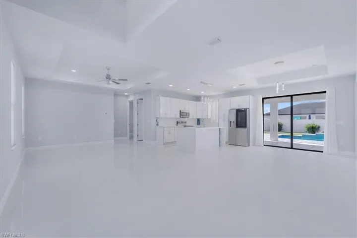 Unfurnished living room with a raised ceiling, recessed lighting, and ceiling fan