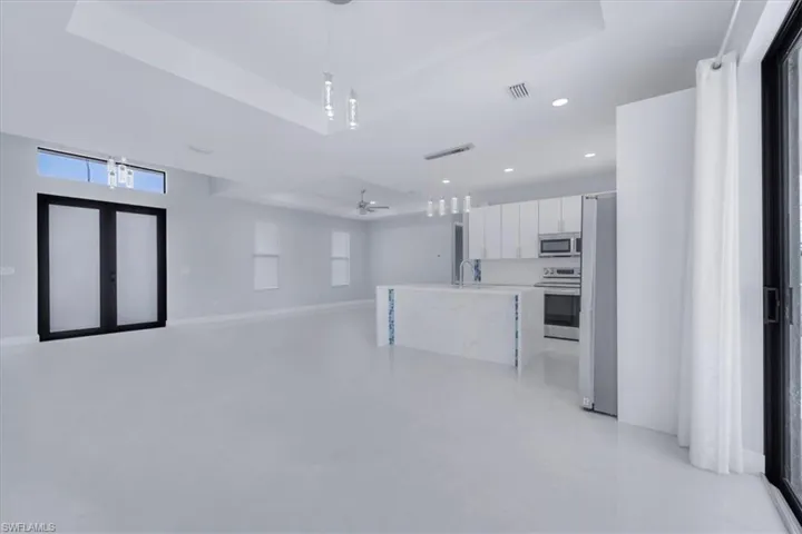 Kitchen featuring pendant lighting, open floor plan, ceiling fan, appliances with stainless steel finishes, and white cabinetry