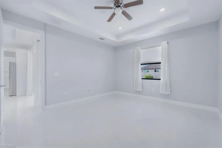 Unfurnished room with a raised ceiling, recessed lighting, and a ceiling fan