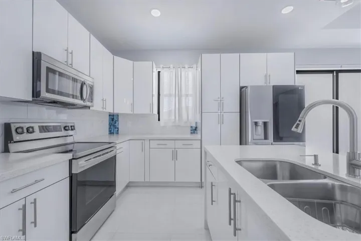 Kitchen with stainless steel appliances, backsplash, light stone countertops, white cabinets, and recessed lighting