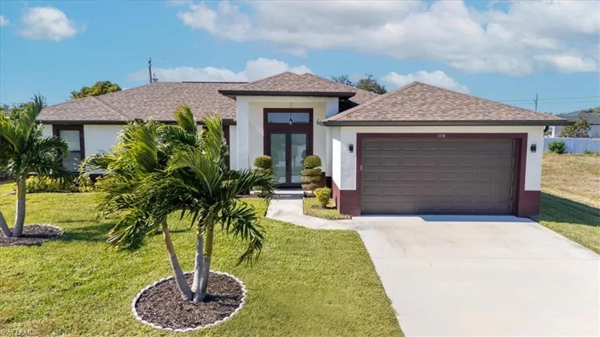 View of front facade featuring a shingled roof, stucco siding, a front lawn, driveway, and an attached garage