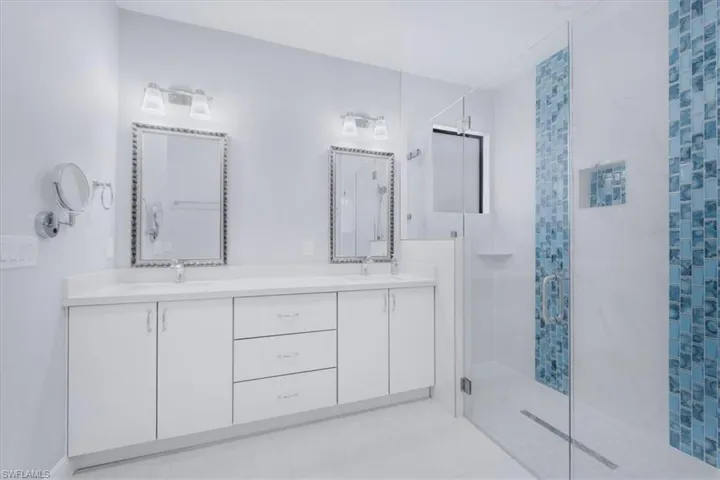 Bathroom featuring a stall shower, double vanity, and light tile patterned flooring