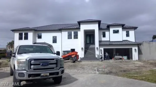 View of front of house featuring a standing seam roof, an attached garage, and driveway