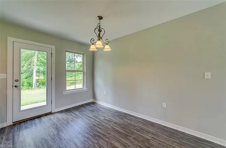 Unfurnished dining area featuring dark wood-style floors and a chandelier