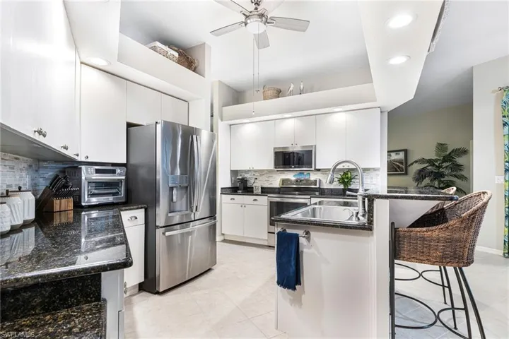 Kitchen featuring white cabinetry, tasteful backsplash, appliances with stainless steel finishes, and light tile patterned floors