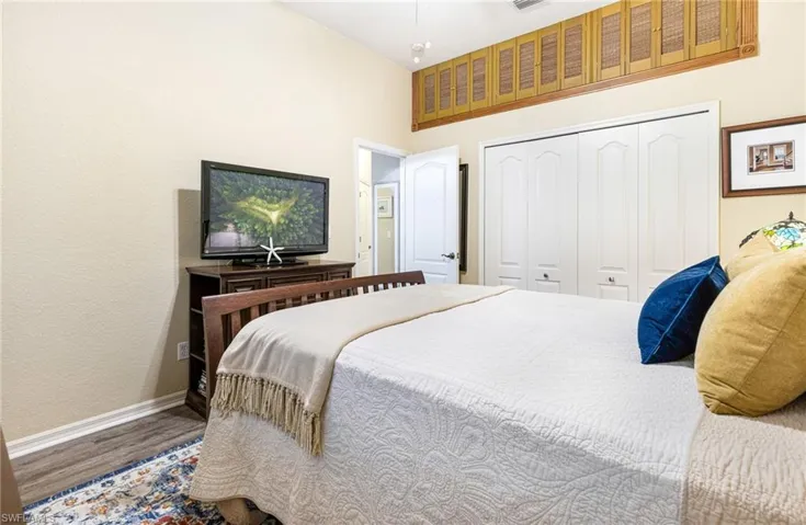 Bedroom featuring wood-type flooring, a closet, and a towering ceiling