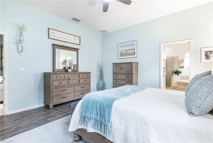 Bedroom featuring ensuite bath, dark hardwood / wood-style floors, and ceiling fan