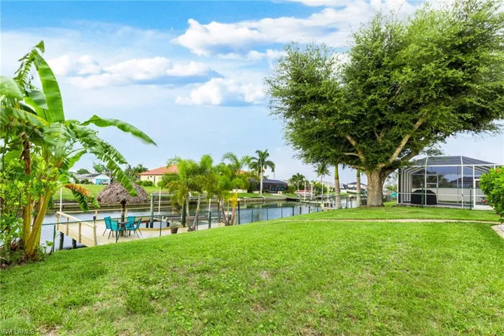 View of yard with a water view, a swimming pool, and glass enclosure