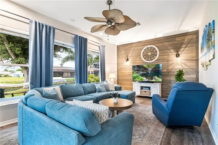 Living room featuring wood walls, wood-type flooring, and ceiling fan