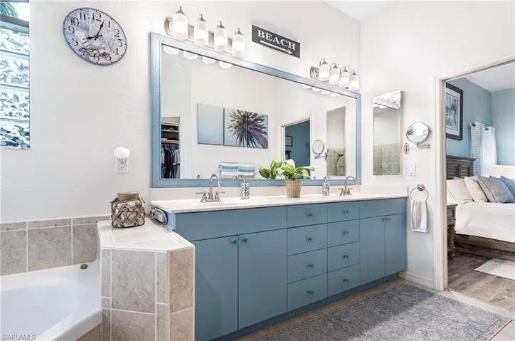 Bathroom with hardwood / wood-style flooring, a bathing tub, and dual bowl vanity