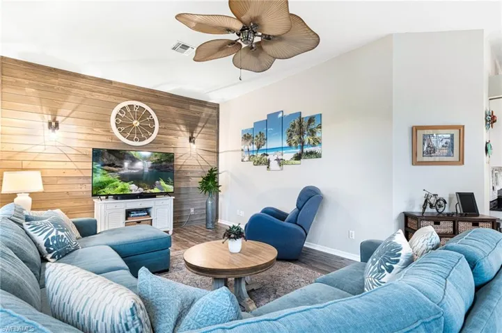 Living room featuring wood-type flooring, wood walls, and ceiling fan