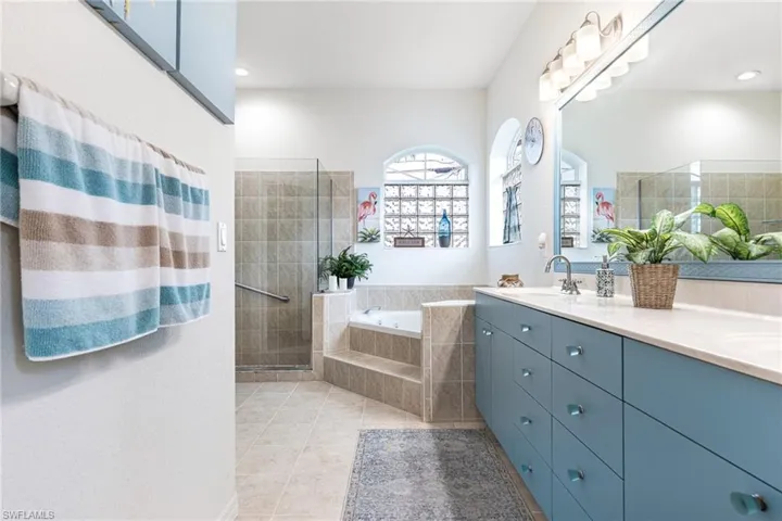Bathroom featuring double vanity, tile patterned floors, and separate shower and tub