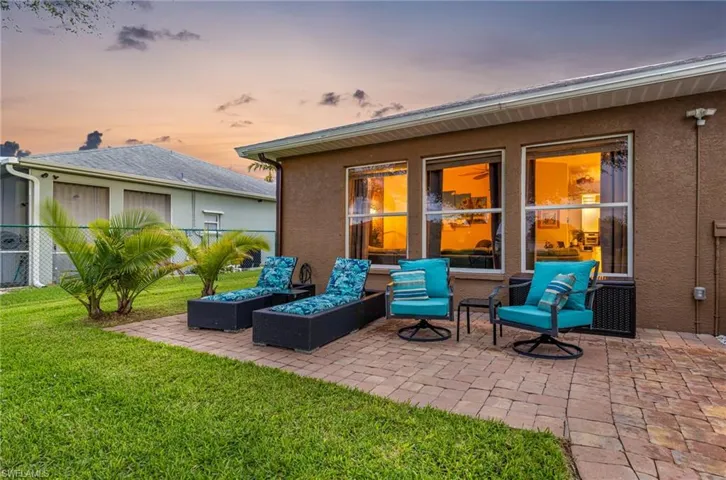 Patio terrace at dusk featuring outdoor lounge area and a lawn