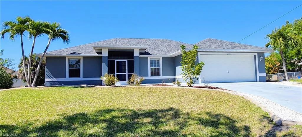 Another view of front of property with stucco siding, a garage, oversized lot.