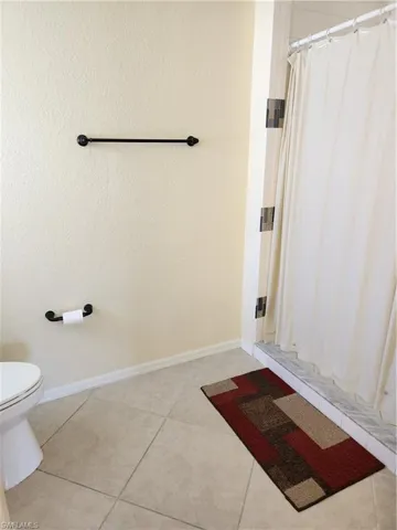 Primary Bathroom featuring a shower stall and light tile patterned flooring.